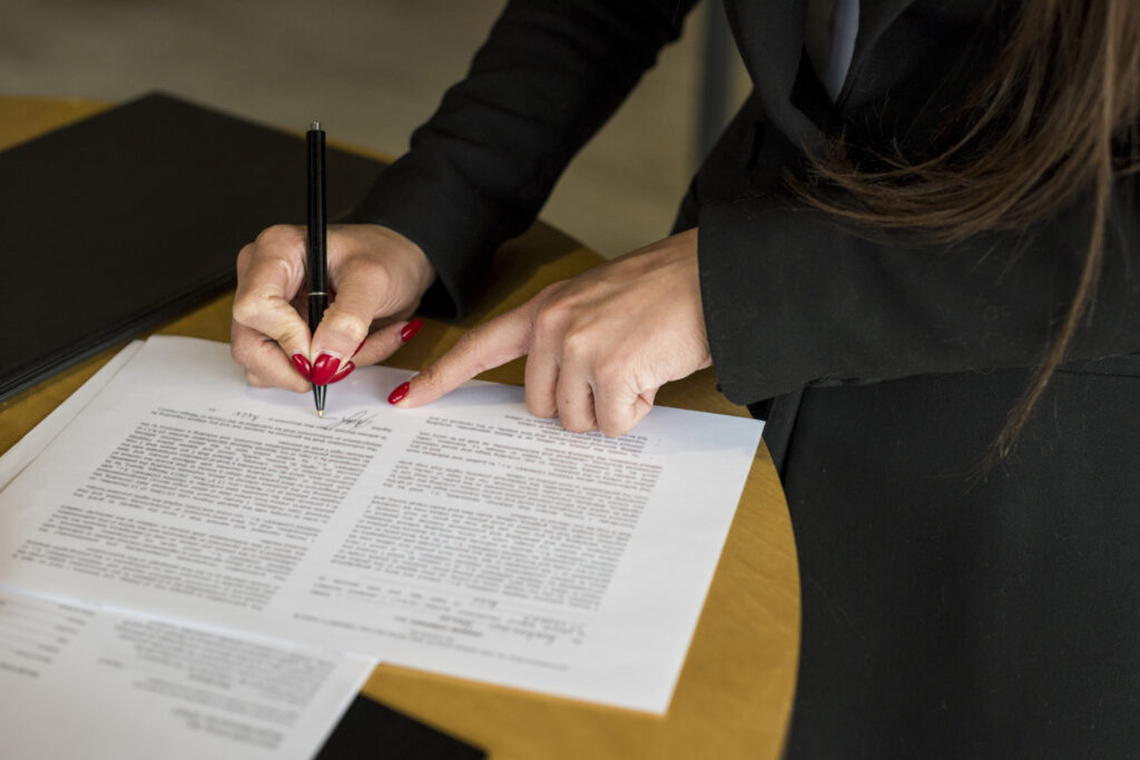 Femme signant des documents juridiques pour illustrer le fait d'être sur la page des mentions légales